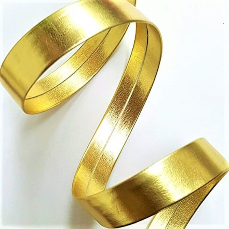 May include: Gold metallic ribbon with a subtle textured finish. The ribbon is rolled up and has a slight sheen.
