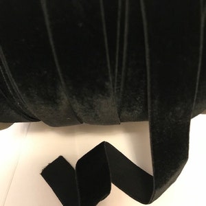 Pu&ograve; includere: Un rotolo di nastro di velluto nero. Il nastro &egrave; largo circa 2,5 cm ed &egrave; mostrato in primo piano.