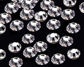 Puede incluir: Una dispersión de piedras de cristal redondas transparentes sobre un fondo negro. Las piedras de cristal son de varios tamaños y tienen una superficie facetada y reflectante.
