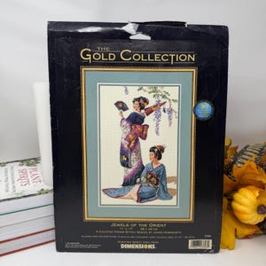 May include: The Gold Collection Jewels of the Orient counted cross stitch kit by Dimensions features a design of two figures in traditional attire. The package measures 11 inches by 17 inches and includes cotton and metallic threads.