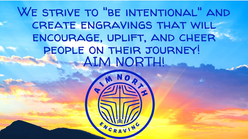 May include: A blue and white logo with the text "AIM NORTH" and "ENGRAVING" against a colorful sunset sky. The text reads "We strive to "be intentional" and create engravings that will encourage, uplift, and cheer people on their journey! Aim North!"