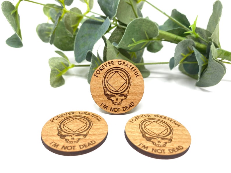 May include: Three wooden round ornaments with the text "Forever Grateful I'm Not Dead" and a skull with a diamond shape inside.