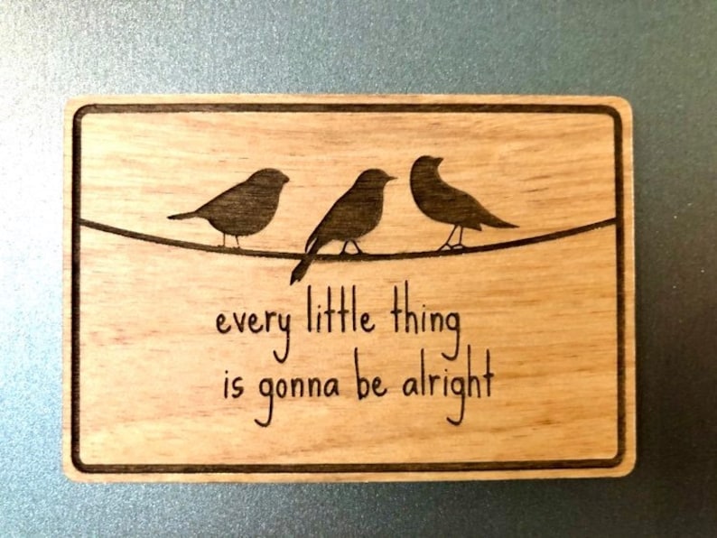 Puede incluir: Un letrero de madera con tres p&aacute;jaros posados en un alambre. El letrero dice "every little thing is gonna be alright".