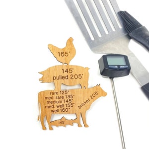 May include: Wooden cutout of a chicken, pig, and cow with internal temperature guidelines for cooking. The text includes "pulled 205", "brisket 205", "165", "145", "rare 125", "med. rare 135", "medium 145", "med. well 155", "well 160".