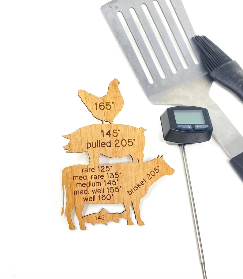 May include: Wooden cutout of a chicken, pig, and cow with internal temperature guidelines for cooking. The text includes "pulled 205", "brisket 205", "165", "145", "rare 125", "med. rare 135", "medium 145", "med. well 155", "well 160".