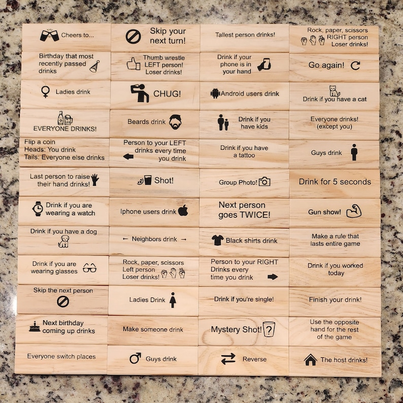 May include: Wooden block game with various drinking prompts. Each block features a different instruction, such as "Drink if you have a cat" or "Skip your next turn!" The blocks are arranged on a light-colored surface.