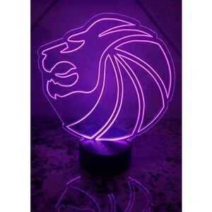 May include: A purple LED night light shaped like a lion's head. The light is on a black base.