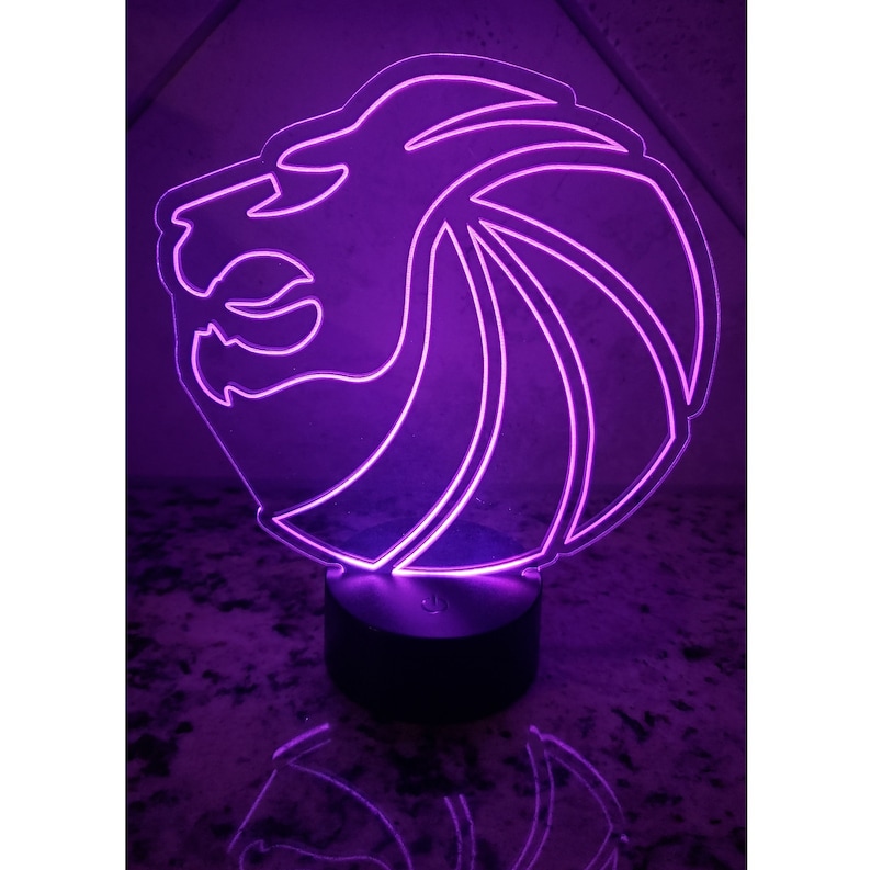 May include: A purple LED night light shaped like a lion's head. The light is on a black base.