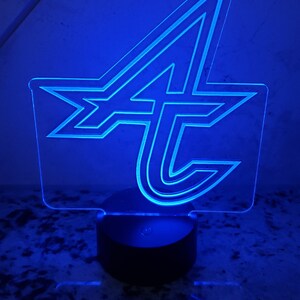 May include: A blue acrylic night light shaped like the letter "A" with a stylized design. The light is on a black base.