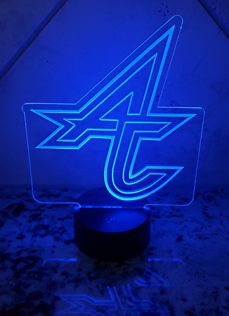 May include: A blue acrylic night light shaped like the letter "A" with a stylized design. The light is on a black base.