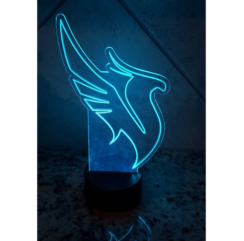 May include: A blue LED night light shaped like a bird with wings spread out. The light is on a black base.