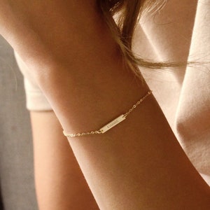May include: A gold chain bracelet with a small rectangular tag that says "KIMMIE".