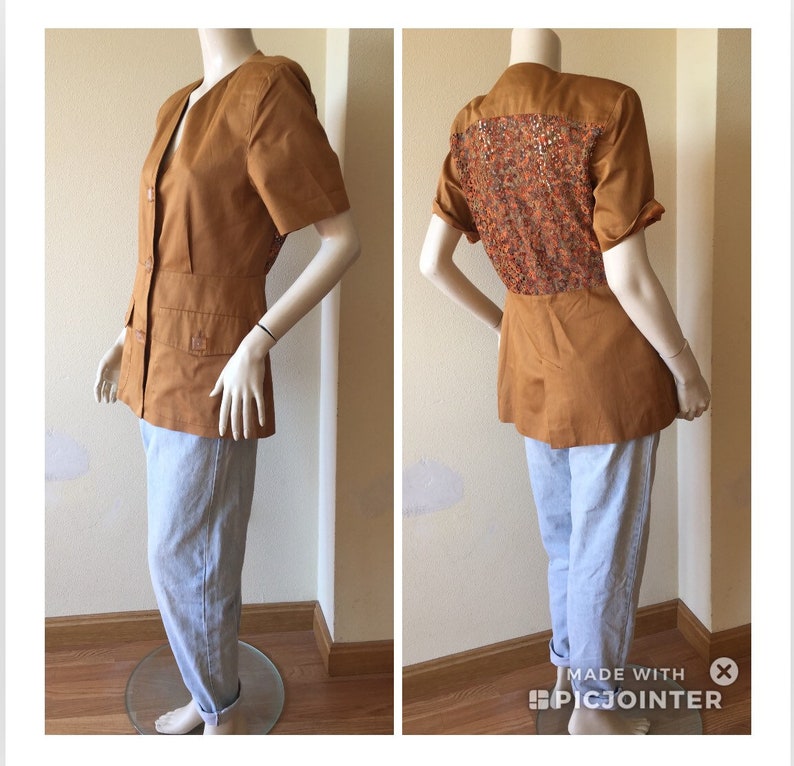 May include: A tan short-sleeved blazer with a decorative patterned back panel. The blazer has a V-neck, button closure, and two front pockets. The mannequin is also wearing light blue trousers.