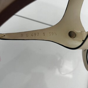 May include: Close-up of a cream-colored sandal strap with a dark brown sole. The strap has the text "R G 497 1 39 1/2" printed on it. The sandal is likely a size 8.5 US.
