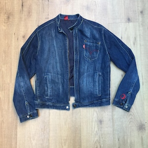 Peut inclure: Une veste en jean bleu avec une fermeture &eacute;clair et un logo Levi's rouge sur la poche. La veste a un col montant et des manches longues.