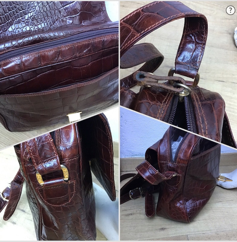 Op de afbeelding: Bruine leren handtas met een krokodillenleer textuur. De tas heeft een handvat aan de bovenkant en een schouderriem. Het heeft een hoofdvak met ritssluiting, een voorvak en goudkleurige hardware. De tas is rechthoekig en heeft een klepsluiting.