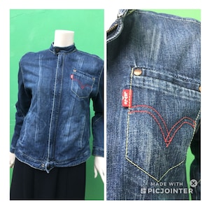 Peut inclure: Une veste en jean bleu avec un col montant, une fermeture &eacute;clair et un logo Levi's rouge sur la poche. La veste a un aspect vieilli et est faite d'un mat&eacute;riau doux et confortable.