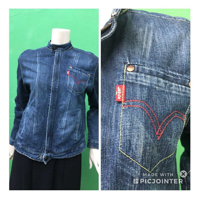 Peut inclure: Une veste en jean bleu avec un col montant, une fermeture &eacute;clair et un logo Levi's rouge sur la poche. La veste a un aspect vieilli et est faite d'un mat&eacute;riau doux et confortable.