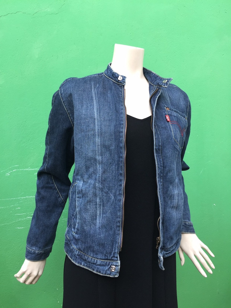 Peut inclure: Une veste en jean bleu avec une fermeture &eacute;clair et un col montant. La veste a un logo Levi's rouge sur la poche gauche.