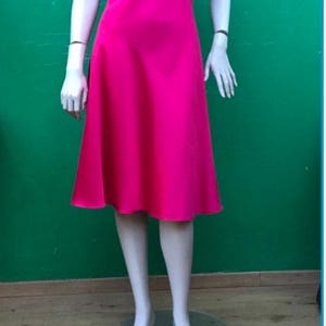 May include: A hot pink sleeveless dress with a sweetheart neckline and a flowing skirt. The dress is on a mannequin and is displayed against a green background.