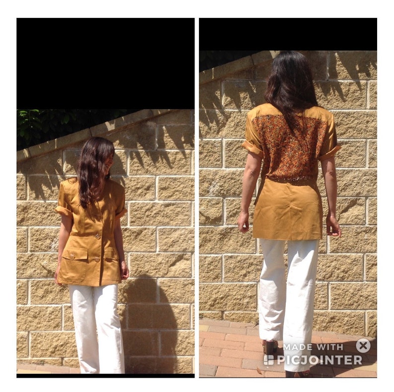 May include: A mustard-coloured short-sleeved tunic with two front pockets and a decorative back panel. The tunic is paired with white trousers. The back panel has a detailed pattern of orange, brown, and yellow. The outfit is suitable for casual wear.