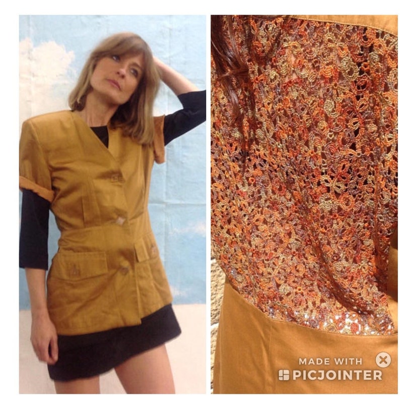 May include: Mustard-coloured short-sleeved jacket with a black undershirt and a black skirt. The jacket has a V-neck, two pockets, and a button closure. The back of the jacket features a detailed, colourful, open-weave design.
