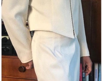 May include: Off-white, textured skirt suit. The jacket has a zip closure and long sleeves. The skirt is knee-length. The suit is made of a woven fabric. The outfit is suitable for business or formal occasions.