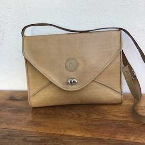 Puede incluir: Un bolso de hombro de cuero marrón con cierre de solapa y un logotipo circular con las letras "F" y "F" en su interior. El bolso tiene una correa marrón.