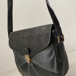 May include: Black leather shoulder bag with a geometric design and a gold clasp.