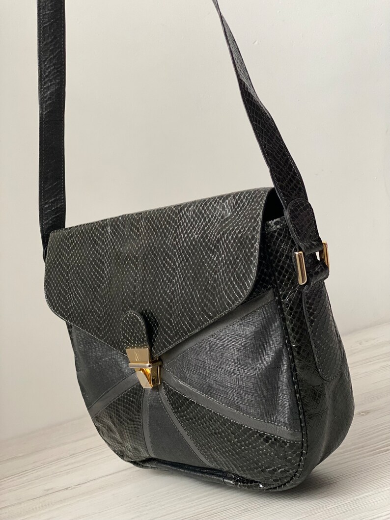 May include: Black leather shoulder bag with a geometric design and a gold clasp.