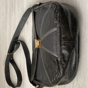 May include: A black leather shoulder bag with a snakeskin pattern and a gold clasp.