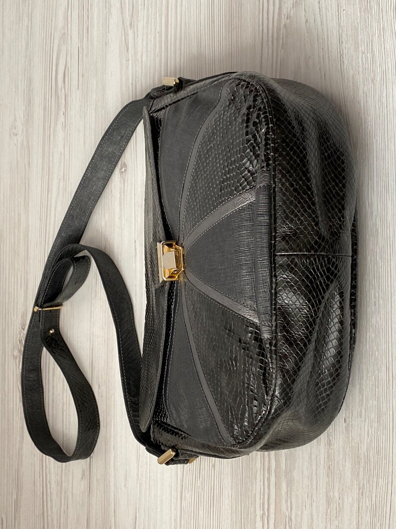 May include: A black leather shoulder bag with a snakeskin pattern and a gold clasp.