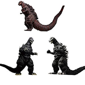 Può includere: Tre figure di Godzilla, una rossa, una nera e una grigia, in diverse pose.