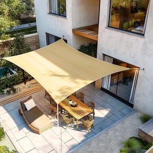 Puede incluir: Una vela de sombra rectangular beige proporciona sombra sobre un conjunto de muebles de patio. El conjunto incluye una mesa de madera con sillas y una tumbona. El patio está rodeado por un edificio blanco y plantas verdes.