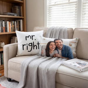 Puede incluir: Un cojín cuadrado blanco con el texto negro "mr. right" y un cojín rectangular con una fotografía en color de una pareja sonriente. Los cojines están colocados sobre un sofá beige con una manta gris texturizada sobre los asientos.