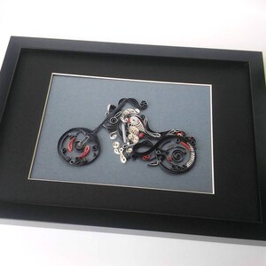 May include: A black framed picture with a grey mount. The picture is of a motorcycle made of paper quilling. The motorcycle is black, white, and red.