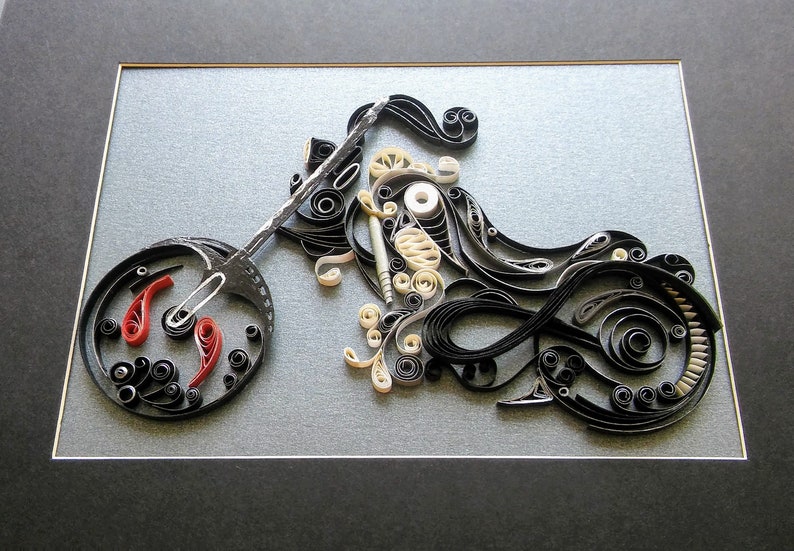 May include: A black and white paper quilling artwork depicting a motorcycle. The motorcycle is framed in a black frame with a grey mount.