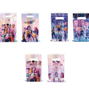 May include: A collection of six clear plastic gift bags featuring colorful illustrations of a pop group. Each bag has a handle and a base. The illustrations include the group members in various poses, with musical notes and other decorative elements.