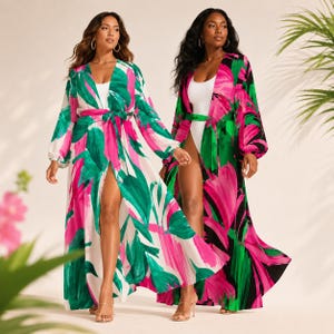 May include: Two long-sleeved, floor-length robes featuring a bold, abstract brushstroke print in vibrant shades of hot pink and emerald green. One robe has a white base, while the other has a black base. Both include a matching tie-waist belt.