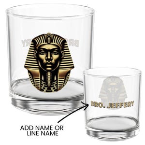 Op de afbeelding: Twee heldere glazen bekers met een goud-zwart farao-ontwerp. Het grotere glas heeft het farao-ontwerp en de tekst "BRO. JEFFERY" in goud. Het kleinere glas heeft het farao-ontwerp en de tekst "BRO. JEFFERY".