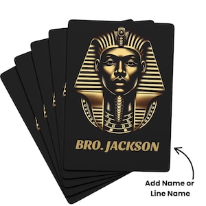 May include: A deck of black playing cards featuring a gold illustration of an Egyptian pharaoh's face. The text "BRO. JACKSON" is printed in gold. The cards are fanned out, showing the design.