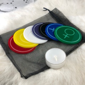 May include: A set of six colourful round coasters with a female symbol design, a white tea light candle, and a black mesh bag.