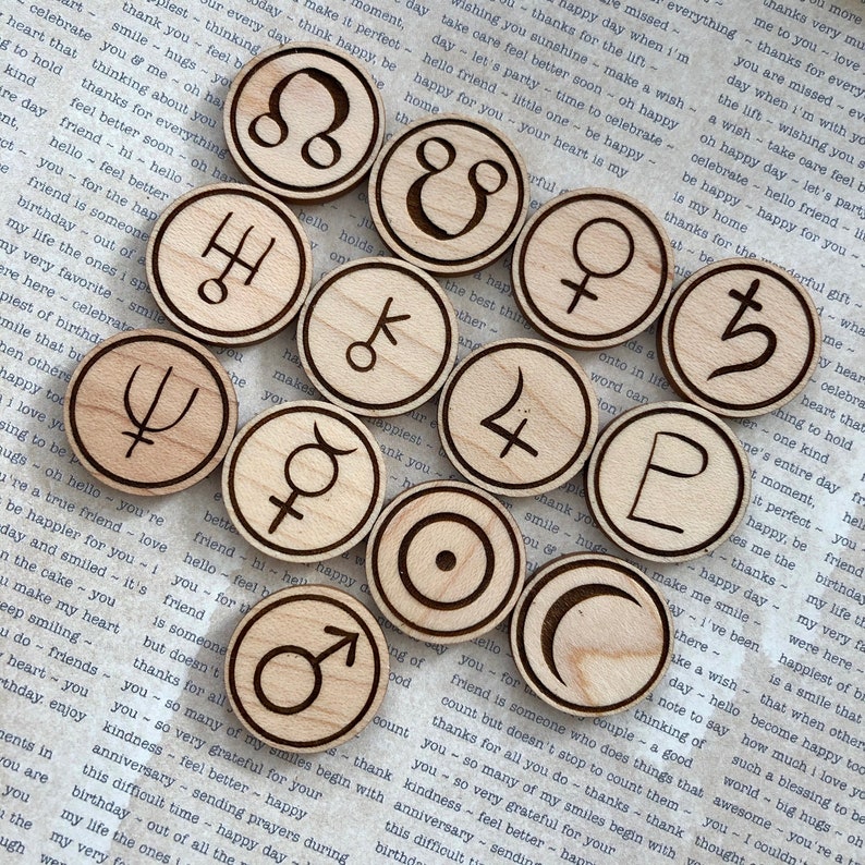 K&ouml;nnte beinhalten: Ein Satz von 12 astrologischen Holzschaftmarken. Jede Marke ist ein Kreis mit einem anderen astrologischen Symbol, das in sie geschnitzt ist. Die Marken sind in einem Kreis auf einem St&uuml;ck Papier mit Text angeordnet.