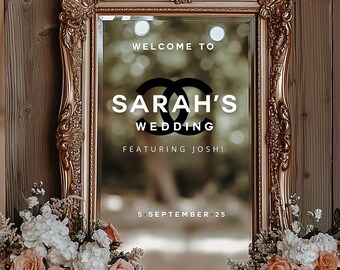May include: Ornate gold framed mirror with the text "WELCOME TO SARAH'S WEDDING FEATURING JOSH!" and the date "5 • SEPTEMBER • 25". The mirror is surrounded by floral arrangements with peach and white roses.