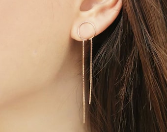 May include: A pair of gold-toned earrings with a small circle at the top and two long chains dangling down.