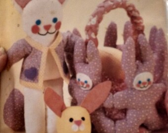 May include: A set of four plush bunny toys, including a white bunny with a purple jacket, a pink bunny with a basket, and two smaller pink bunnies. The toys are made of soft fabric and have embroidered details.