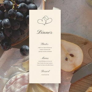 Może przedstawiać: Proste, eleganckie menu kolacji z sercem na górze. Menu zawiera propozycje przystawek, dań głównych i deserów. Tekst brzmi: "Kolacja", "Przystawka", "Grillowana sałatka Cezara z parmezanem", "Kalamary z cytryną i", "Szparagi z czerwonymi migdałami", "Dania główne", "Łosoś z koperkiem i cytryną na kukurydzy", "Rack of Lamb z ziemniakami rozmarynowymi", "Kremowy makaron z pesto z grillowanym kurczakiem", "Deser", "Ciasto brownie cytrynowe"