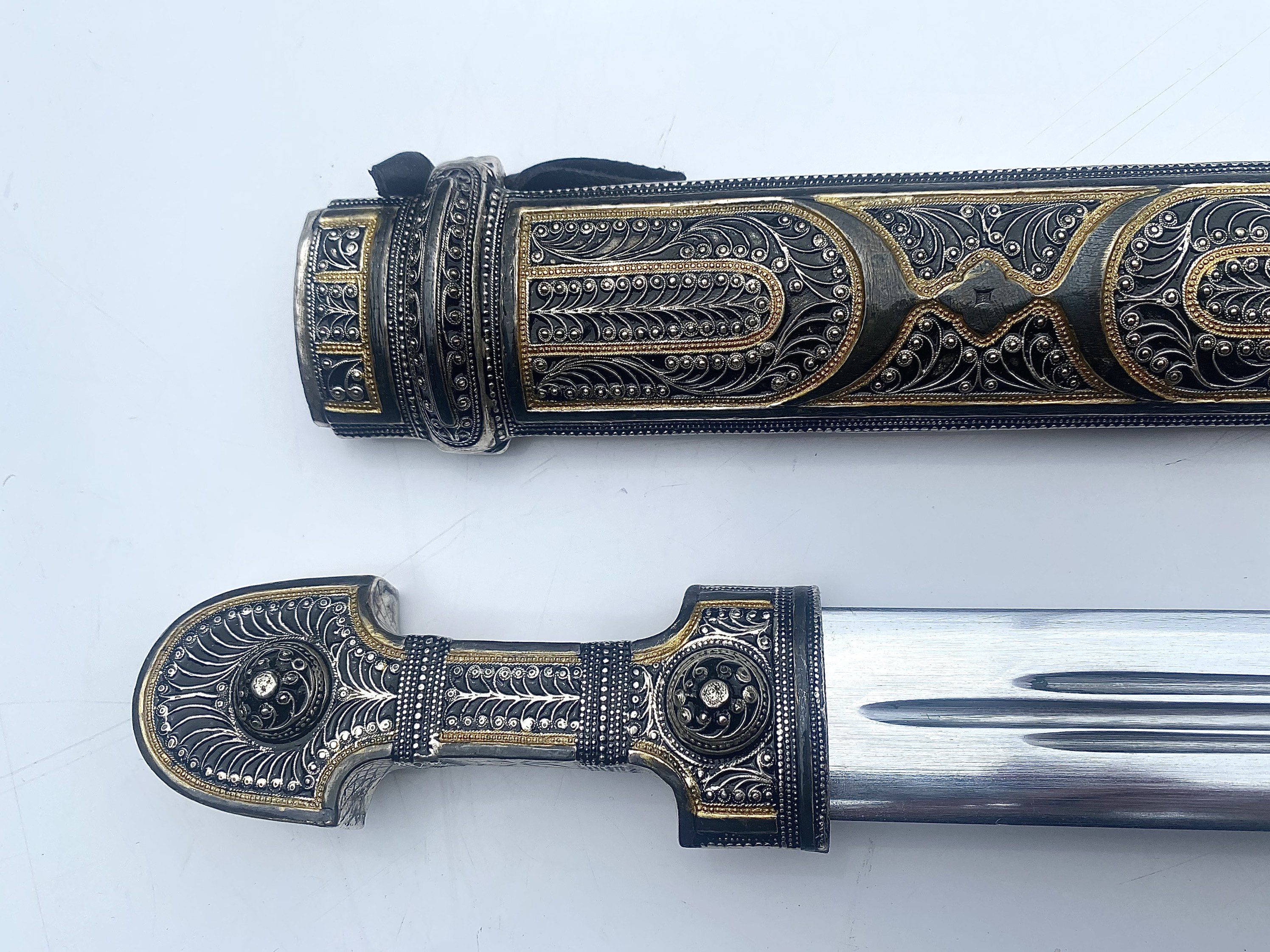 Caucasian qama or kindjal dagger, the 15cm pointed double edged blade with  centre fuller and two-piece horn grip; in nickel plated scabbard with  panels of figures and script L28.5cm overall; and east 