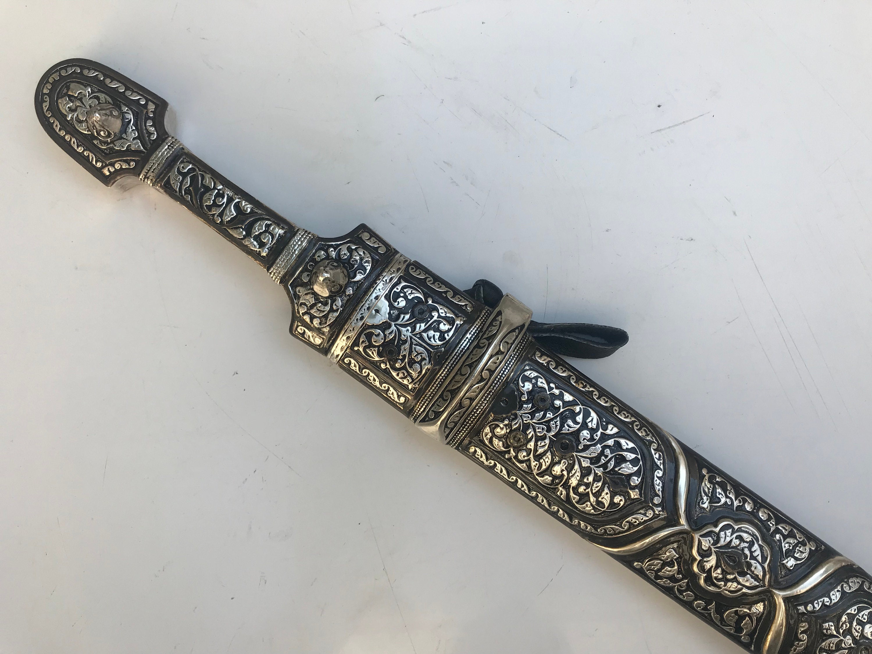 Caucasian qama or kindjal dagger, the 15cm pointed double edged blade with  centre fuller and two-piece horn grip; in nickel plated scabbard with  panels of figures and script L28.5cm overall; and east 