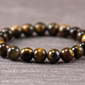 May include: A brown and gold beaded bracelet made of tiger's eye stones.